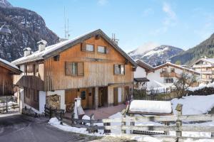 a wooden house with a fence in the snow at Villetta Crepaz in Canazei