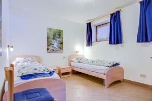 a room with two beds and a window with blue curtains at Villetta Crepaz in Canazei