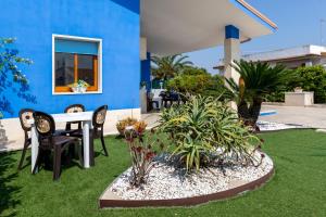 a blue house with a table and chairs and plants at Villa Lindarelax in Santa Maria del Focallo