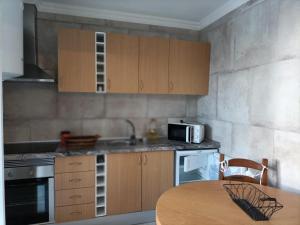 a kitchen with wooden cabinets and a table with a microwave at Akademia House - Santarém in Santarém