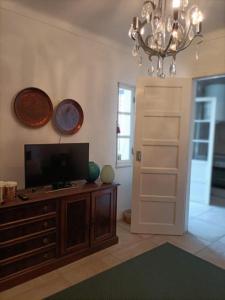 a living room with a television and a chandelier at Akademia House - Santarém in Santarém