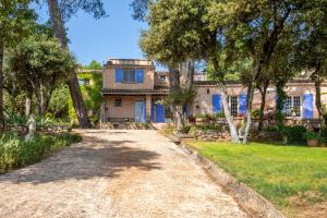 a house with blue doors and a dirt road at Bastide Lou Pèbre D’aï in La Roquebrussanne