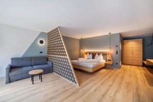 a bedroom with a bed and a couch at Aktiv Lodge Meran - Garden One in San Martino