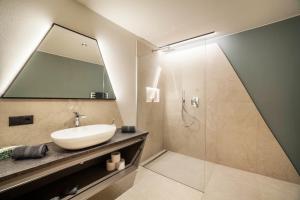 a bathroom with a sink and a shower with a mirror at Aktiv Lodge Meran - Garden One in San Martino +37 photos
