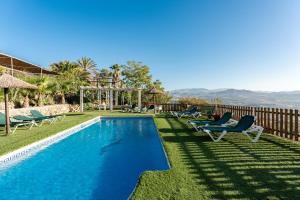 a swimming pool with lawn chairs and a fence at Casa Rural Salrima in Alora
