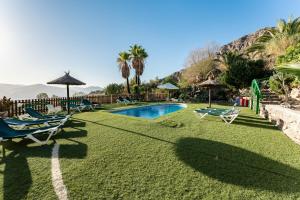 a pool with chairs and umbrellas in a yard at Casa Rural Salrima in Alora
