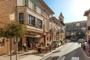 a group of people sitting at tables on a city street at Es Figueral in Campos