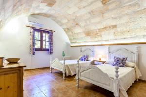 a bedroom with two beds and a stone wall at Es Figueral in Campos +18 photos