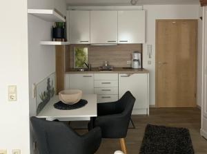 a kitchen with white cabinets and a table and chairs at Haus Zum Haiden in Bodman-Ludwigshafen