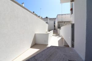 an alley between two white buildings with the sun shining at Casa Caterina a Otranto in Otranto