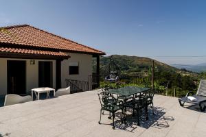 a patio with a table and chairs on a balcony at Casa Mourelo Alojamento Local in Ponte da Barca