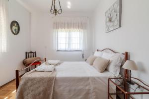 a white bedroom with a bed and a window at Casa Mourelo Alojamento Local in Ponte da Barca