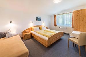 a bedroom with two beds and a chair in it at Ferienwohnung Jakob in Schwendau