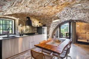 a kitchen with a wooden table and a stone wall at Modern Heritage House in Imperia