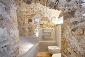 a bathroom with a white toilet and a stone wall at Modern Heritage House in Imperia +37 photos