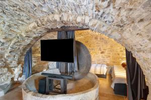 a living room with a tv in a stone wall at Modern Heritage House in Imperia