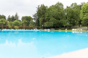 a large pool of blue water with chairs and trees at Nice Lake view apartment in Ispra