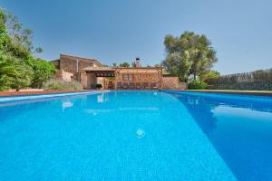 a large blue swimming pool in front of a house at Son Soler - Can Torres in Islas Baleares