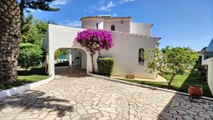 a white house with purple flowers on the side at Villa Palmeira Galé Beach in Albufeira