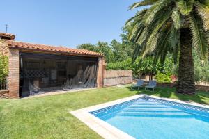 a backyard with a swimming pool and a palm tree at Casa Pont in Tarragona