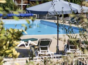 a swimming pool with chairs and an umbrella and a table at Appartement paisible Richelieu in Chaveignes