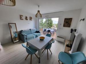 a living room with a table and blue chairs at Appartement paisible Richelieu in Chaveignes