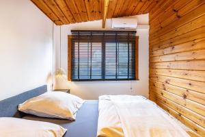two beds in a bedroom with a wooden wall at La Casa Holzwiesen in Starzach