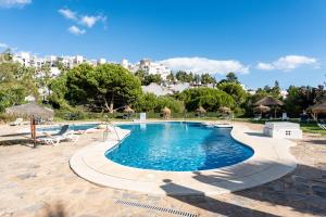 a swimming pool with chairs and a city in the background at Casa Feliz in Mijas