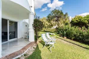 a patio with two chairs on the grass at Casa Feliz in Mijas