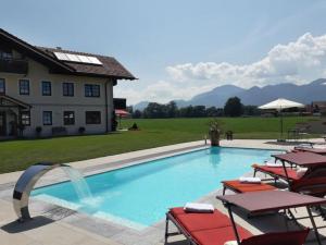 a swimming pool with chairs and a house at Ferienhaus Annelies in Übersee
