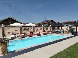 a swimming pool with chairs and umbrellas next to a house at Ferienhaus Annelies in Übersee
