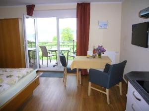 a room with a table and chairs and a balcony at Baumanns Ferienhof Am See in Bettnau