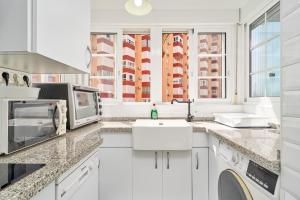 a white kitchen with a sink and a microwave at Primera línea con terraza A104 in Torrox