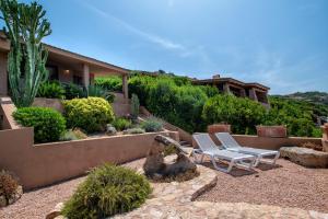 a yard with two chairs and plants and a house at Villa Sirius - sea view - wellness in Costa Paradiso