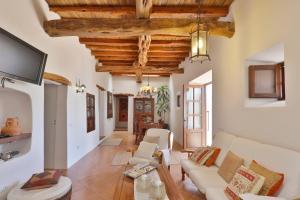 a living room with white furniture and wooden ceilings at Can Caseres in Santa Eularia des Riu