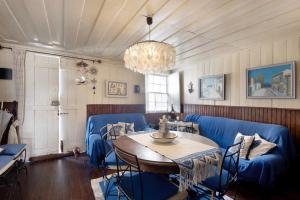 a living room with blue chairs and a table and a chandelier at Casa dos Afectos - Costa Nova in Gafanha da Encarnação