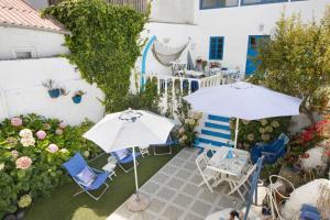 a patio with two umbrellas and chairs and flowers at Casa dos Afectos - Costa Nova in Gafanha da Encarnação