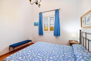ein Schlafzimmer mit einem Bett und einem Fenster mit blauen Vorhängen in der Unterkunft Luisa 1 in Conil de la Frontera + 18 Fotos