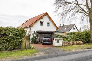 a white house with a truck in the garage at Hütte im Heidekreis in Lindwedel