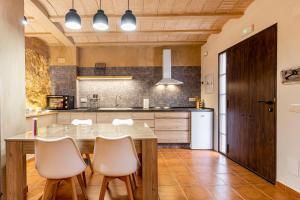 a kitchen with a wooden table and white chairs at Entre Eras Aptos Rurales La Bodega in Ademuz +12 photos