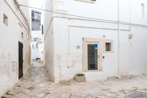 an alley with white buildings and a door at Arco Antelmy in Ceglie Messapica