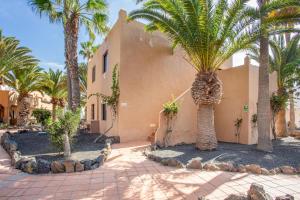 a building with palm trees in front of it at Oasis Duna_ Casa Elena Pool in Corralejo