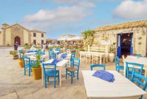 a patio with tables and blue chairs and a building at L' oro dei Magi San Lorenzo in Reitani