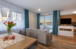 a living room with a dining room table and a television at Appartements Bank Am See in Immenstaad am Bodensee