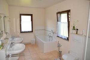 a bathroom with a tub and two sinks and a bath tub at Ferienwohnung Dürnbach in Albstadt