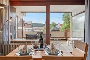 a table with a bottle of wine and glasses on a balcony at Schwarzwaldliebe mit Pool, Sauna in Schönwald
