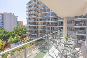 a balcony with a glass table and chairs and a building at Cala alta in Benidorm