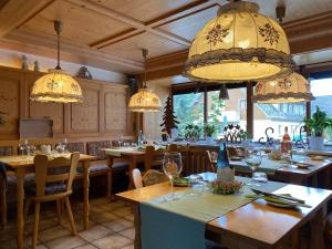 a restaurant with tables and chairs and chandeliers at Pension Linde in Höchenschwand