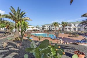 a resort with a swimming pool and palm trees at Relax Holidays Corralejo in Corralejo