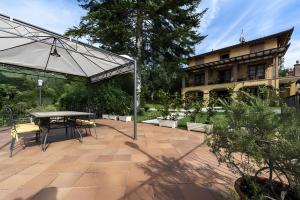 a patio with a table and chairs and an umbrella at All Inclusive Villa Con Piscina in Camaiore